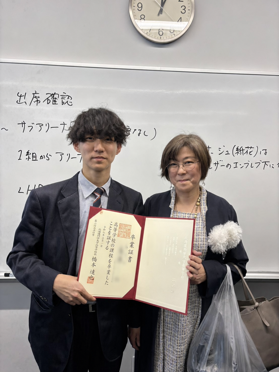 卒業証書を手にする卒業生と保護者